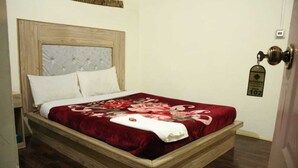 A wooden bed with a floral bedspread and two pillows. - Baltit Heritage Inn (Karimabad)