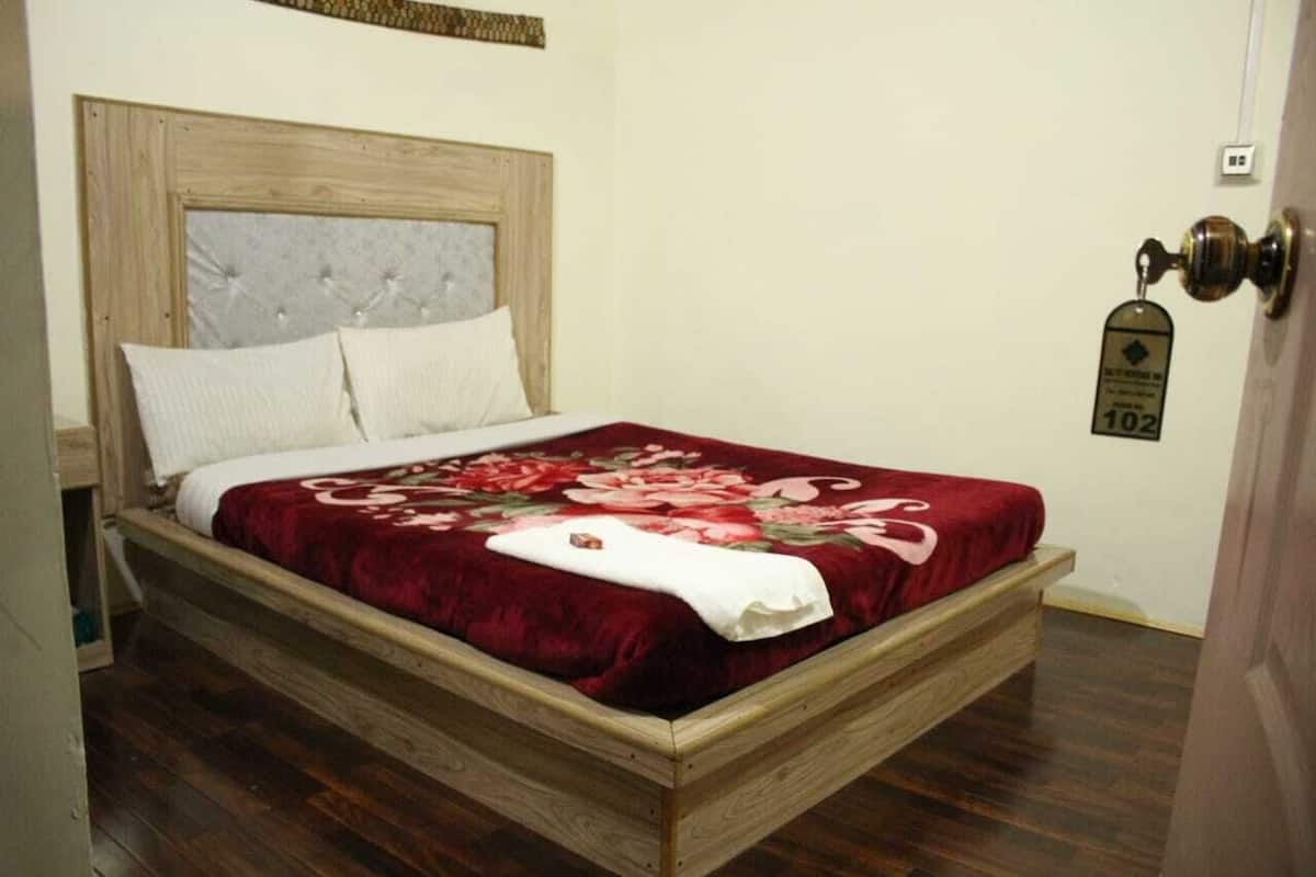 A wooden bed with a floral bedspread and two pillows.