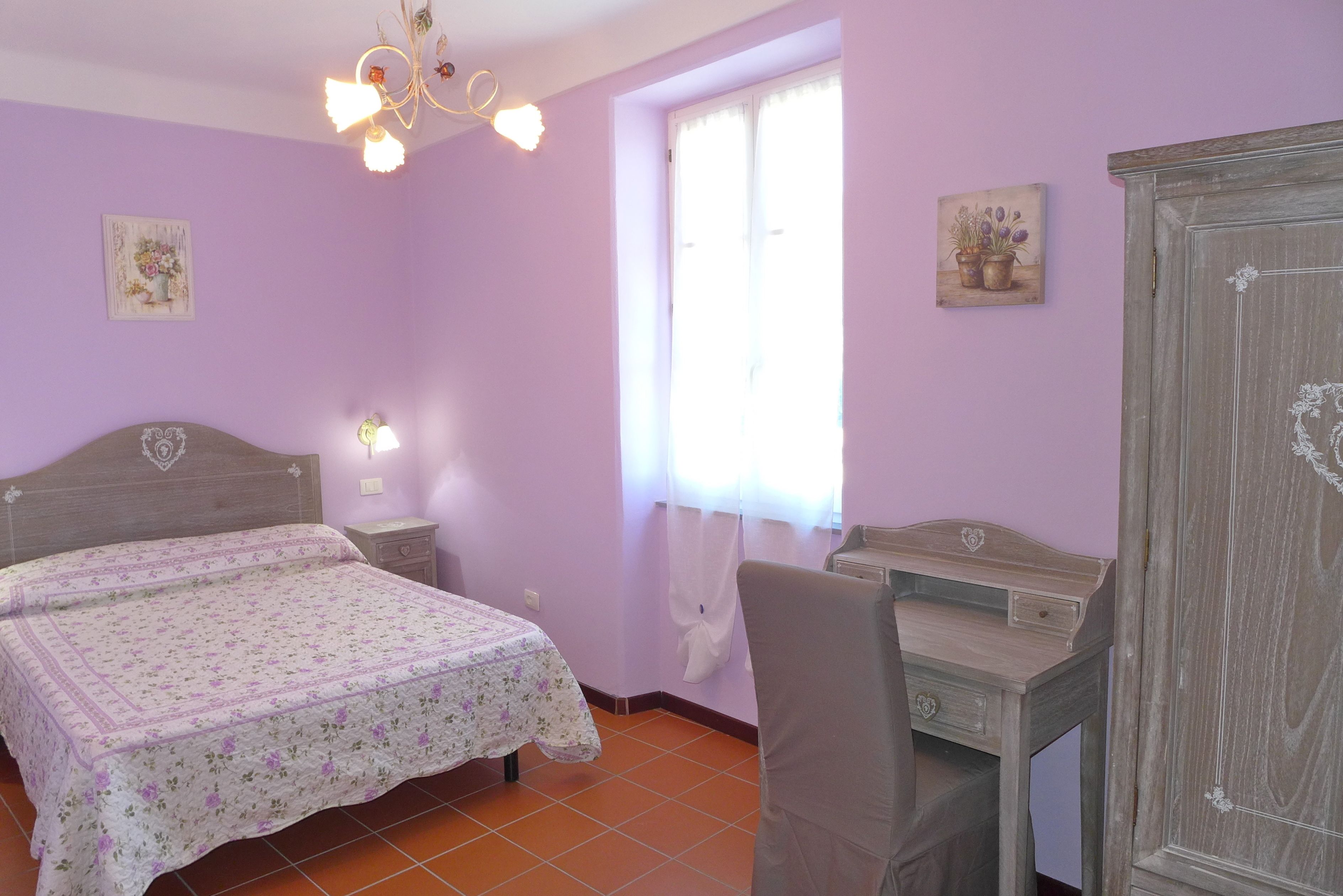 A bedroom with a bed, a desk, and a wardrobe.