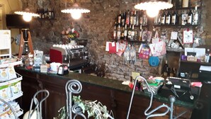 A bar area with a stone wall, shelves of liquor bottles, and a coffee machine. - Hotel Paese Corvara (Beverino)