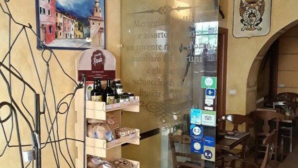 A restaurant interior with a wine rack, a menu board, and a dining area. - Hotel Paese Corvara (Beverino)