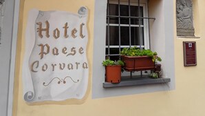 A building with a sign reading "Hotel Paese Corvora" and a window with potted plants. - Hotel Paese Corvara (Beverino)