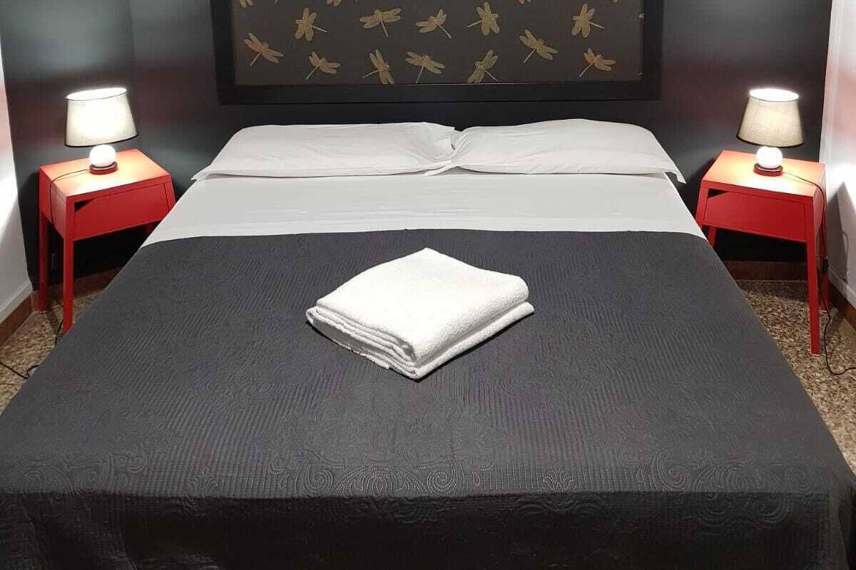 A hotel room with a bed, two nightstands with lamps, and a wall with a dragonfly pattern.