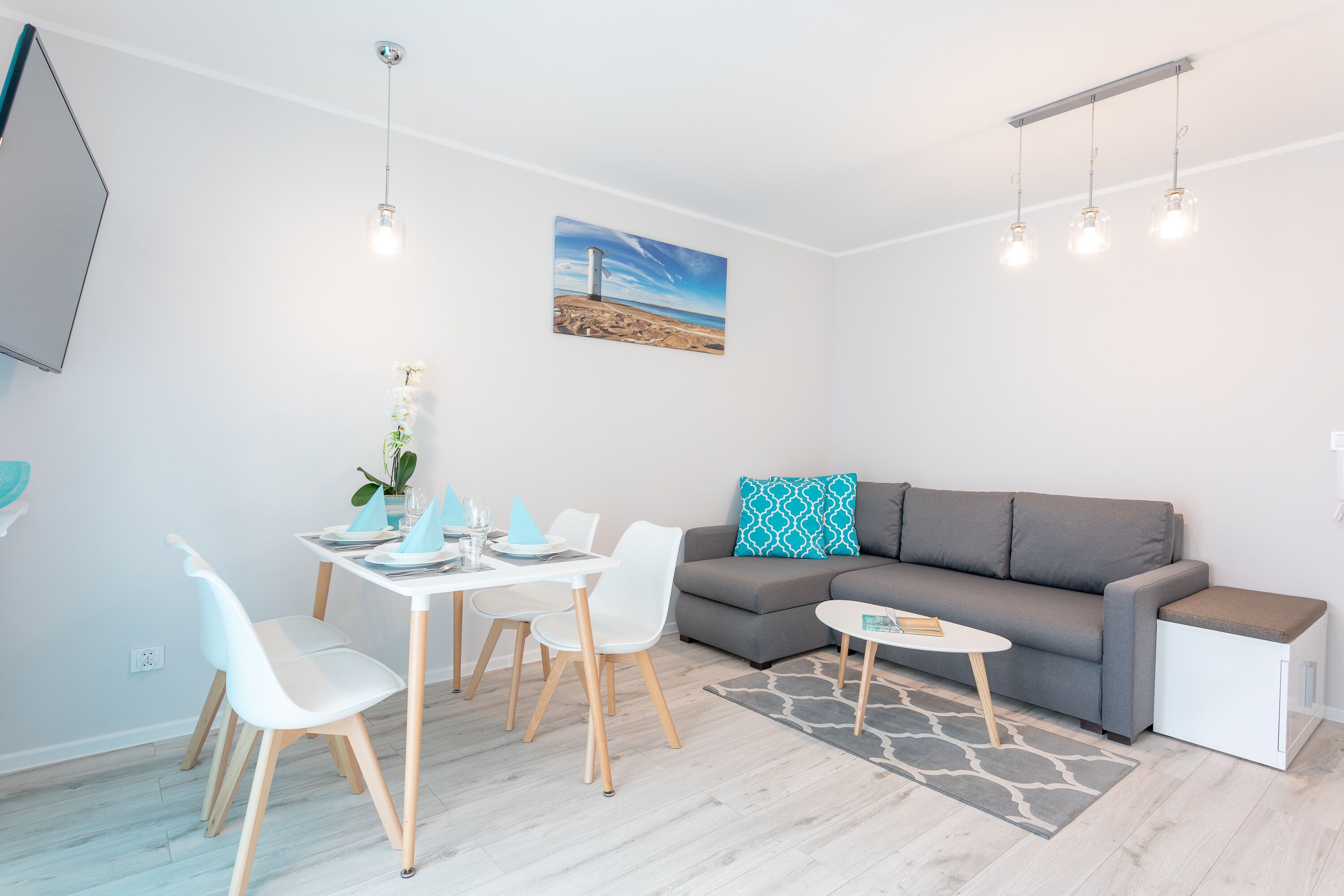 Una sala de estar moderna con un sofá gris, sillas blancas, una mesita y un cuadro en la pared.