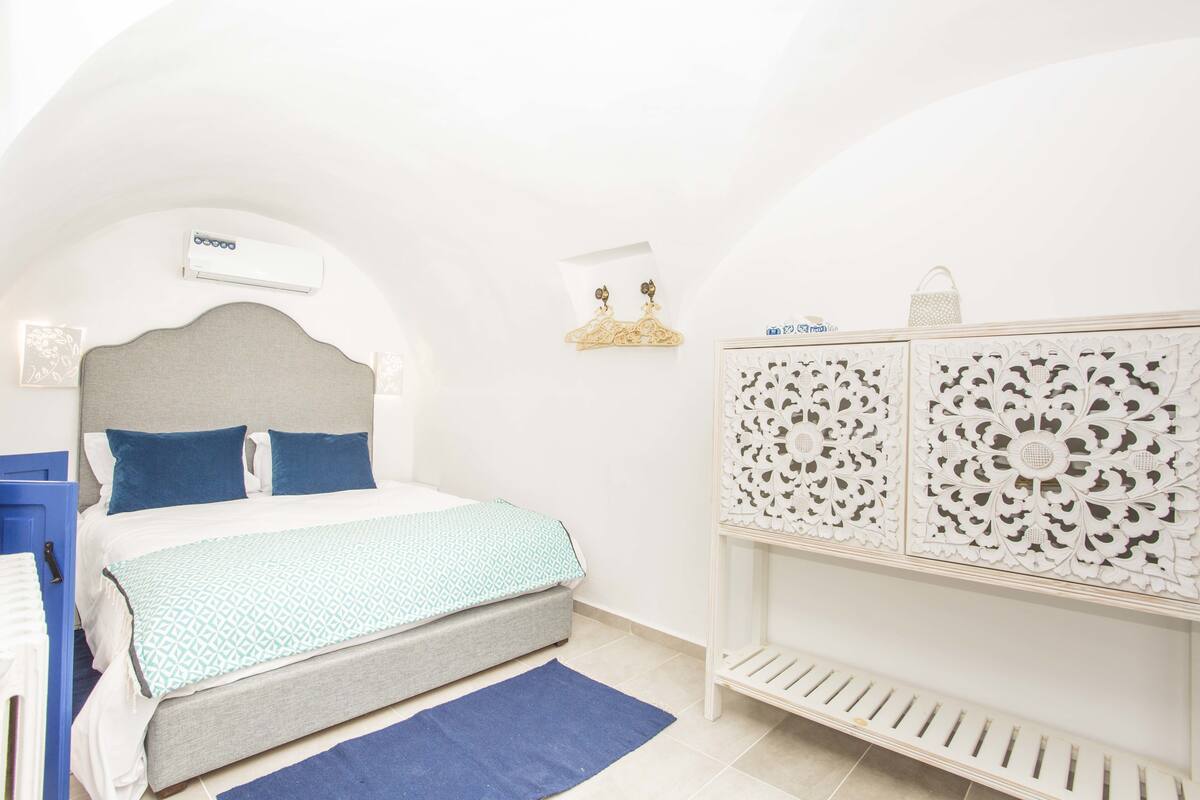 Un dormitorio con cama, mesita de noche, armario y aire acondicionado de pared.