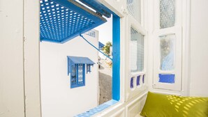 A narrow corridor with a window and a blue awning, leading to a white building with a blue door and window frames. - Appartement Les Musiciens (Sidi Bou Said)