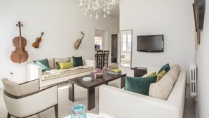 A modern living room with a sofa, chairs, a coffee table, and a TV. - Appartement Les Musiciens (Sidi Bou Said)