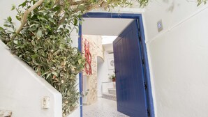 A narrow hallway with a blue door, white walls, and a tiled floor. - Appartement Les Musiciens (Sidi Bou Said)