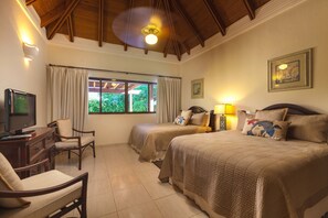 Un dormitorio con dos camas, un escritorio con televisor, una silla y una ventana con cortinas.