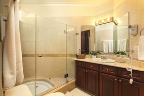 Un baño moderno con ducha de vidrio, tocador con lavamanos y un espejo grande.