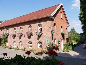 Ein Backsteinhaus mit Bogenfenstern, einem geneigten Dach und Blumenkästen an den Fensterbänken.