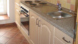 A kitchen with beige cabinets, a stainless steel sink, and a tiled backsplash. - Bleckmanns Hof (Werne)
