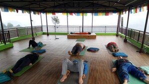 Et overdækket udendørsområde med mennesker, der ligger på måtter, måske til yoga eller afslapning.