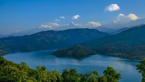 Et bjergrigt landskab med en sø og skovområder.