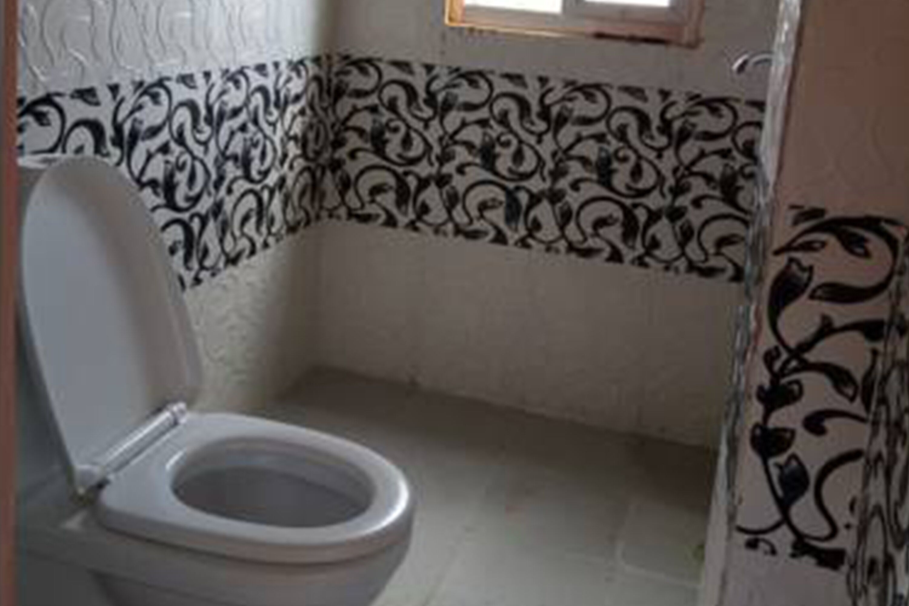 A bathroom with a toilet, patterned wall tiles, and a shower curtain.