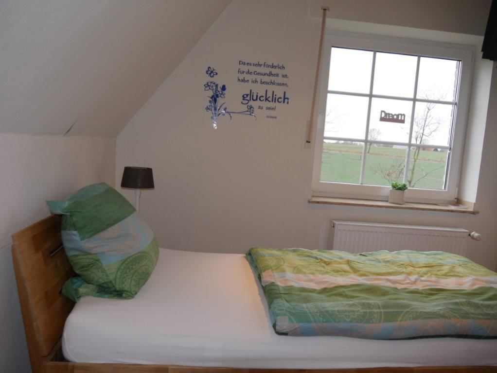 A bedroom with a bed, a window, a wall decoration, and a radiator.