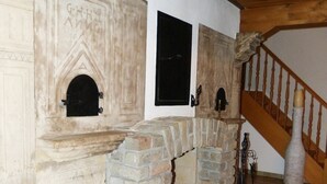 Una chimenea de piedra con chimenea, una escalera de madera y un suelo de baldosas.