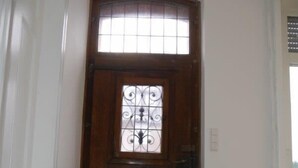 Una puerta de madera con un panel de vidrio decorativo y una pequeña ventana encima.