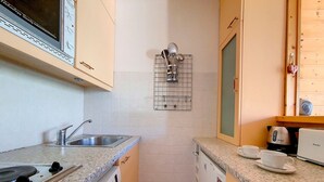 A compact kitchen with a Bosch stove, a sink, a microwave, and a coffee maker. - Spacious apartment for 6, steps from slopes, balcony with Masse view (Les Menuires)