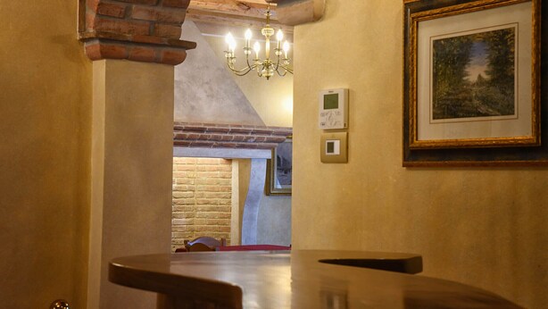 Ein gemütliches Interieur mit Kamin, einer Kristallleuchtre und einem gerahmten Gemälde an der Wand.