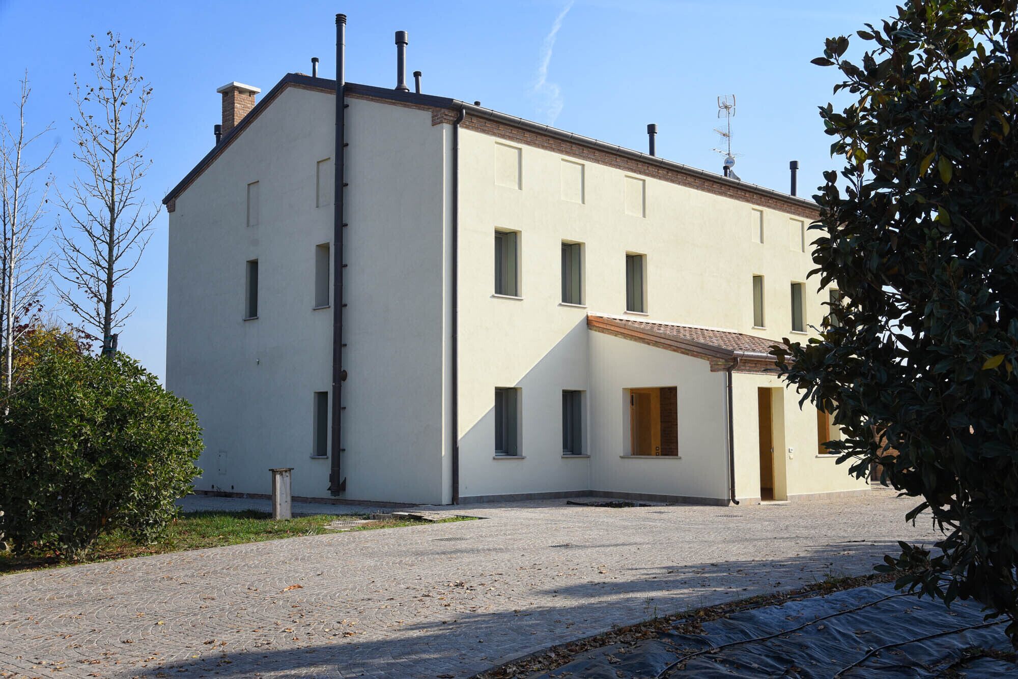 A two-story building with a flat roof, rectangular windows, and a small entrance.