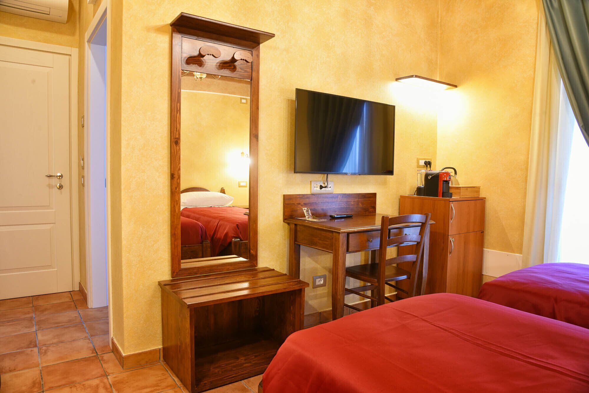 Una habitación de hotel con una cama, un escritorio con una silla, un televisor y un armario.