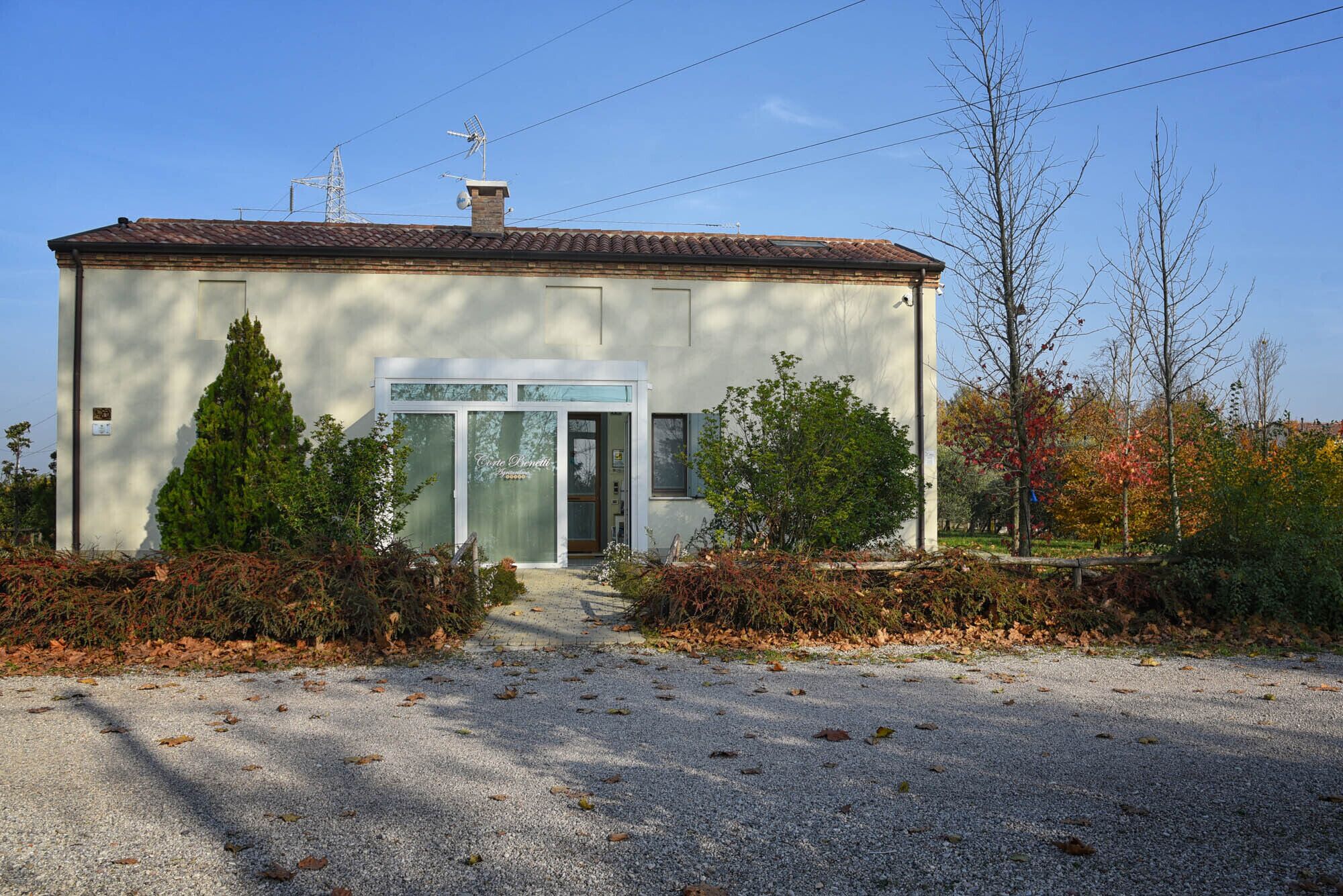 Un piccolo edificio con tetto in tegole, una porta con un cartello e un vialetto sterrato.