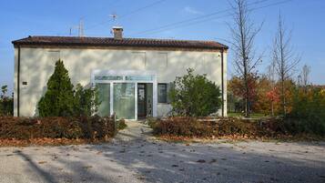 Un piccolo edificio con tetto in tegole, una porta con un cartello e un vialetto sterrato.