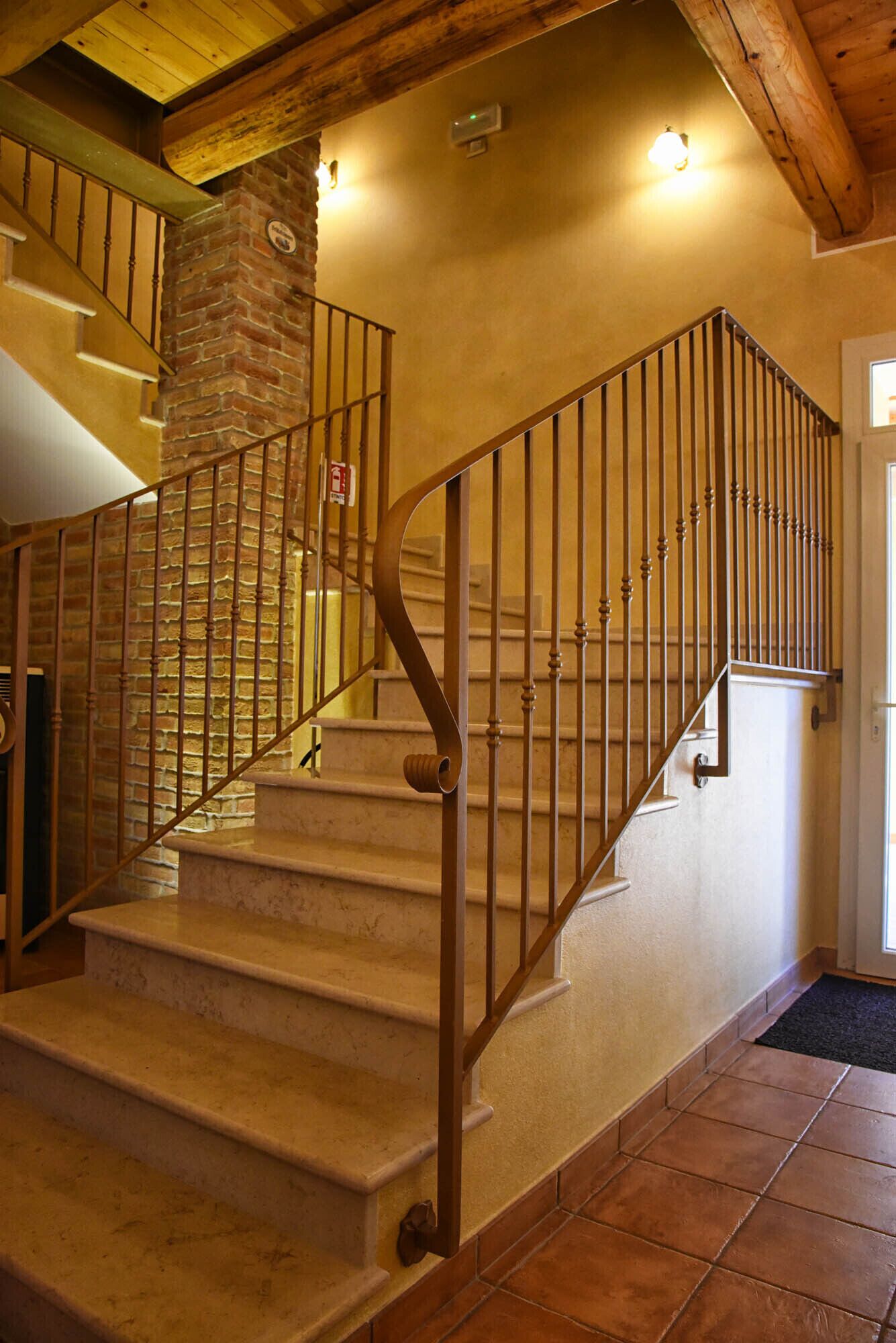 A staircase with a stone pillar, metal railing, and a door at the top.