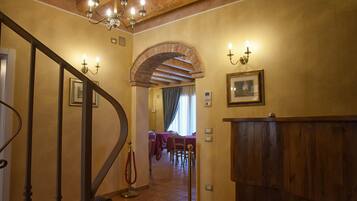 Eine prächtige Treppe mit einem Chandelier, ein Holzbüro und ein Essbereich mit Tischen.
