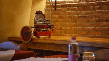 Una habitación con pared de ladrillo, banca de madera, máquina roja y una botella sobre una mesa.
