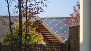 Ein Haus mit geneigtem Dach, Solaranlagen und einem Holzzaun.