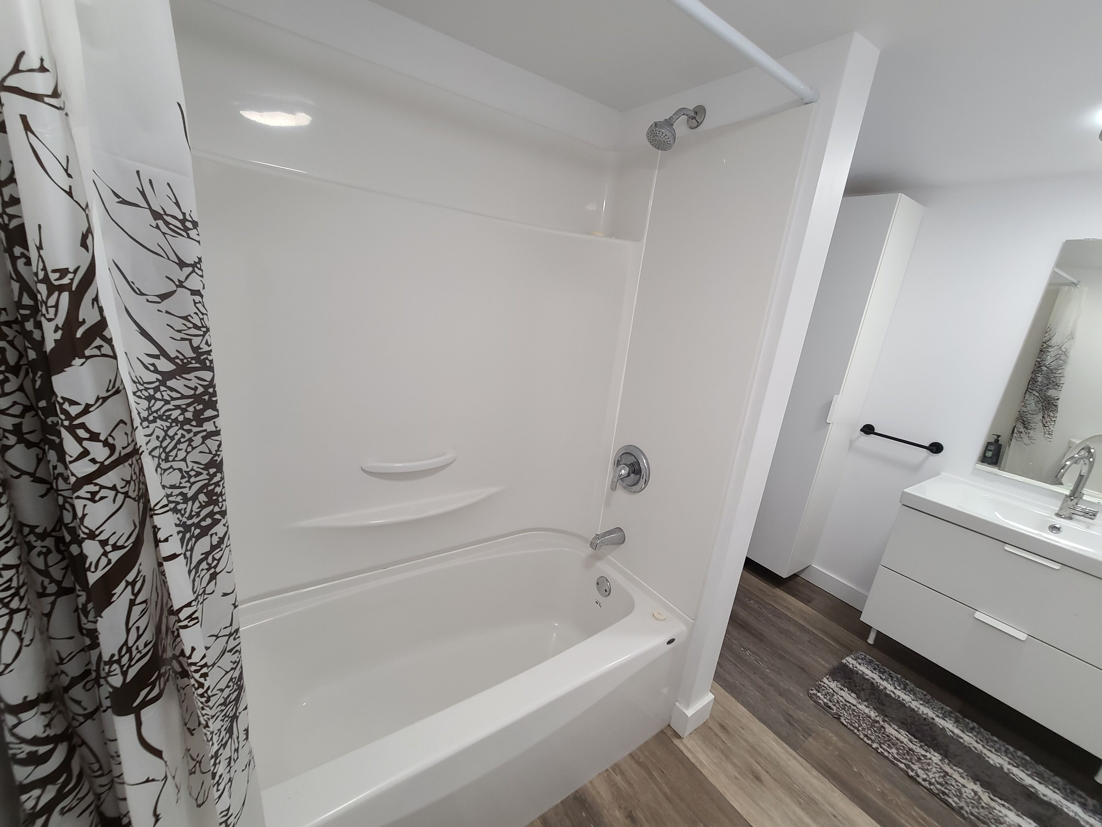 Une salle de bain moderne avec une baignoire blanche, une douche et un meuble-lavabo avec un miroir.