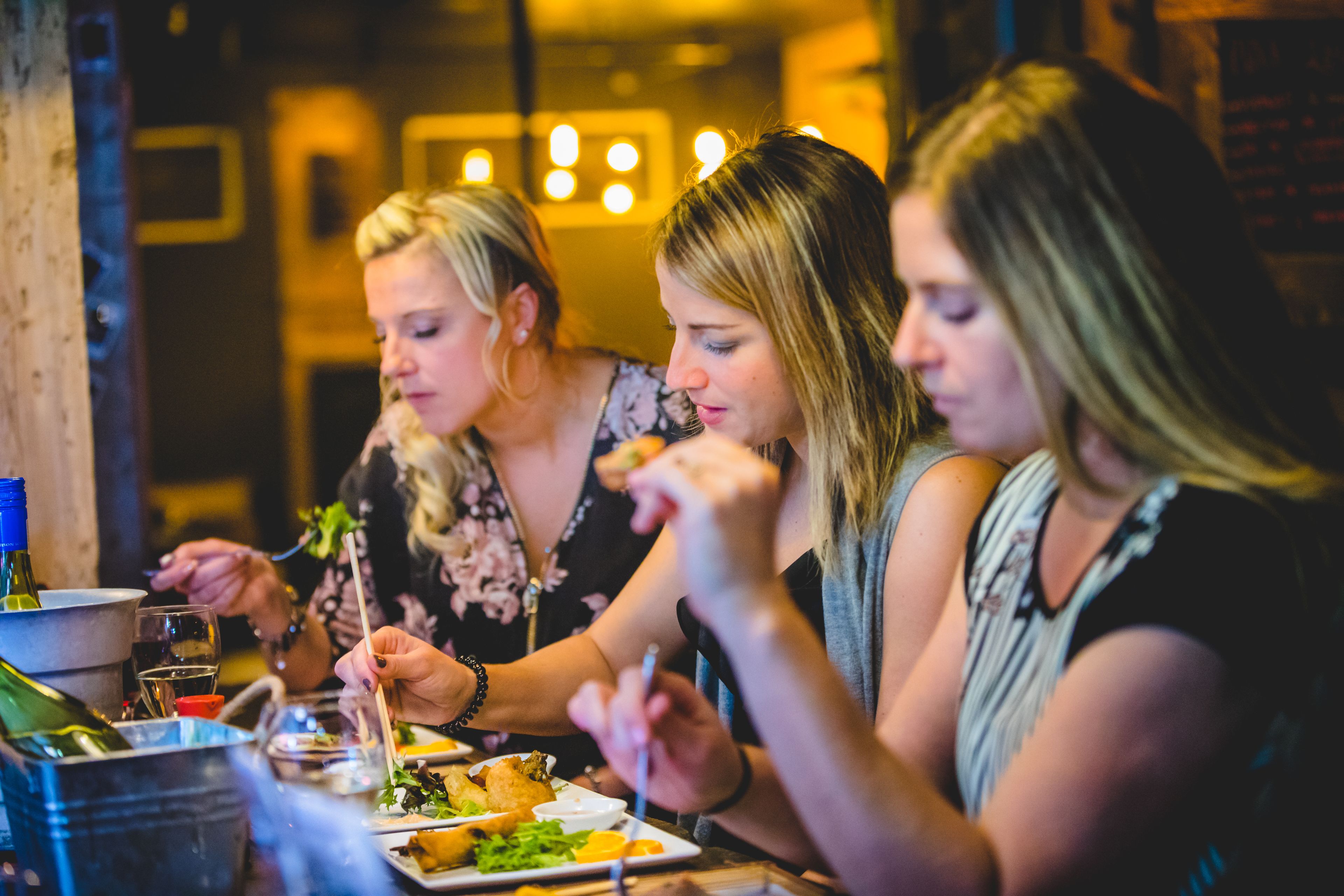 Three people dining at a table with various dishes and drinks.