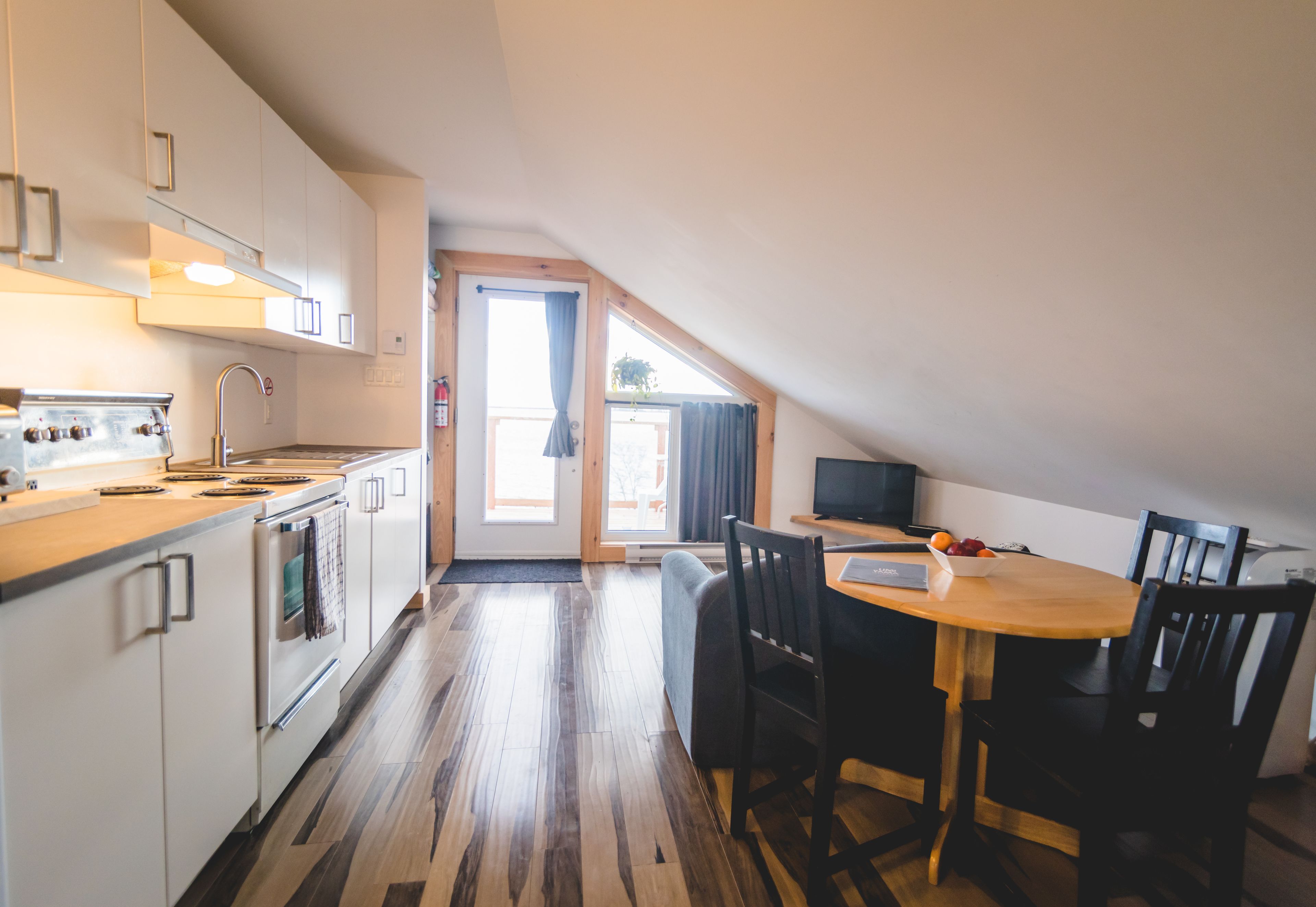 A modern kitchen with white cabinets, a wooden countertop, and a dining area with a wooden table and chairs.