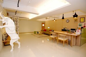 Uma sala de estar moderna com uma escultura de cavalo branco, um sofá, uma mesa de jantar com cadeiras e uma área de cozinha.