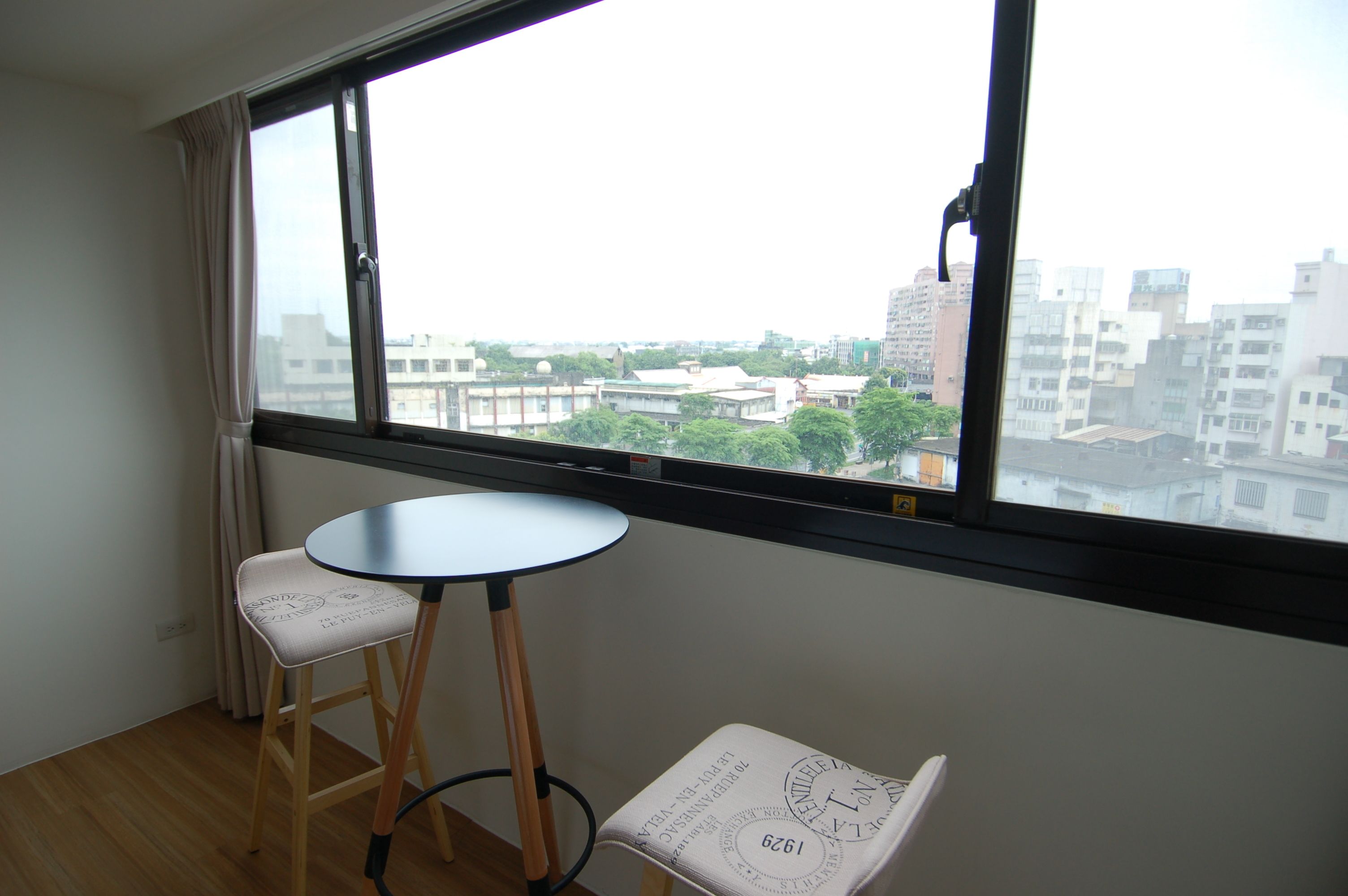 A room with a large window, a round table, and two chairs.
