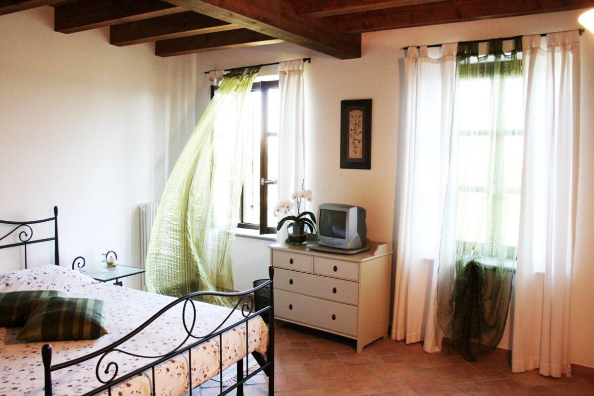 Un dormitorio con cama, una mesita, un aparador y televisor.