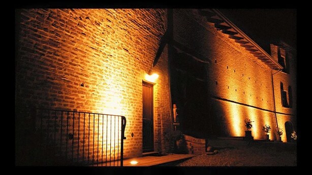 Een bakstenen gebouw met een verlichte ingang en een metalen hek.
