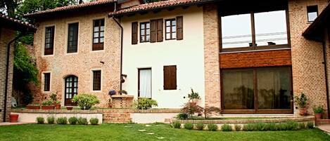 Una casa de dos pisos con fachada de ladrillo, ventanas amplias y un césped bien cuidado.