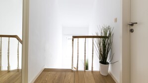 A hallway with wooden flooring, a white door, and a potted plant. - B&B Daya (Leuven)