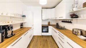 A modern kitchen with white cabinets, a wooden countertop, a coffee machine, an oven, and a toaster. - B&B Daya (Leuven)