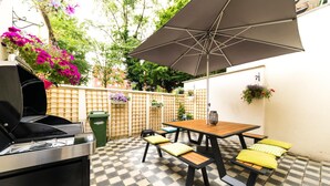 A patio with a grill, outdoor table, benches, and an umbrella. - B&B Daya (Leuven)