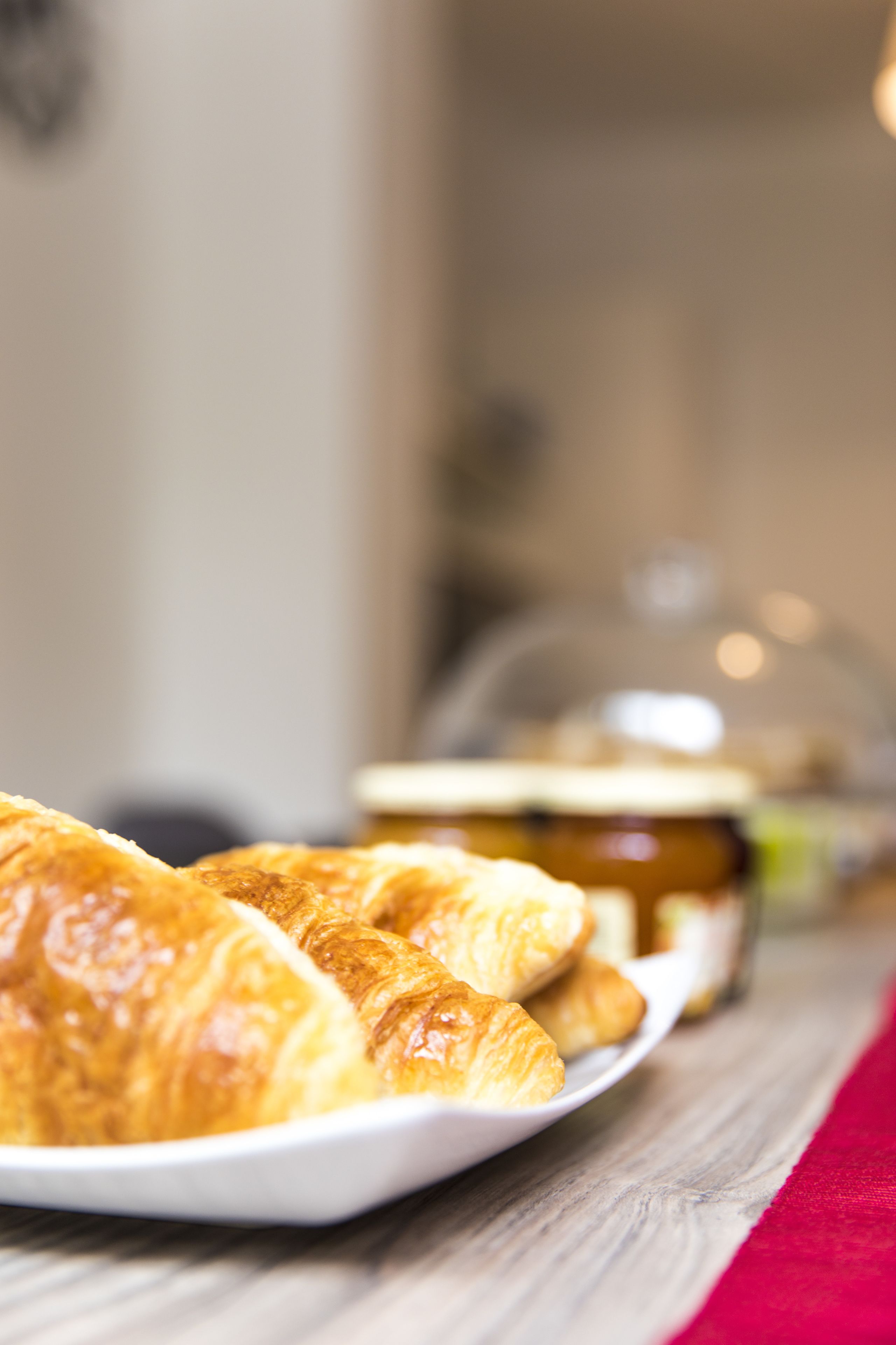 A plate of croissants on a wooden table with a blurred background.