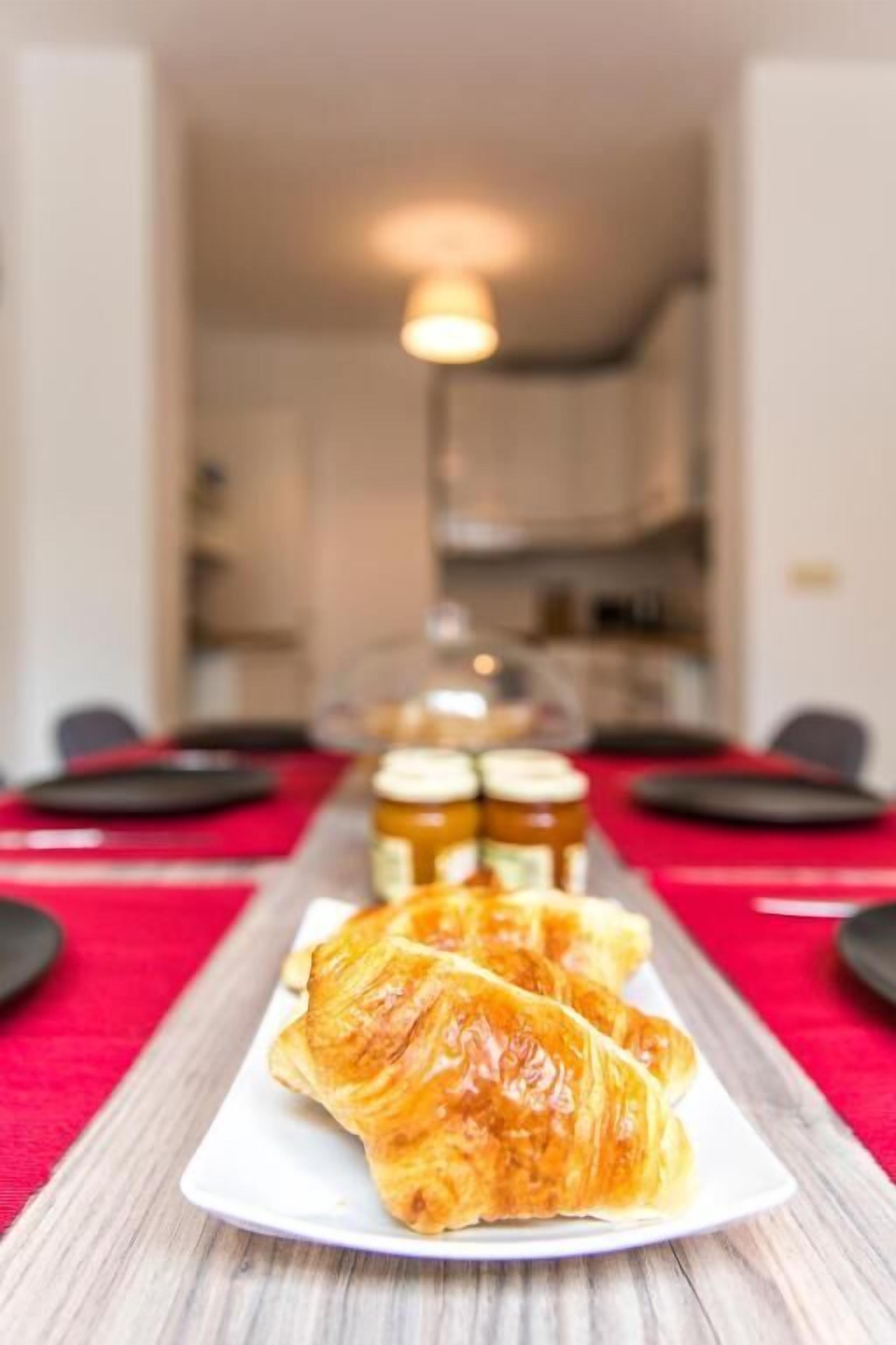 A dining table with croissants and jars of jam.