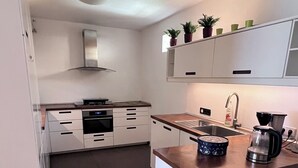 A compact kitchen with white cabinets, a wooden countertop, a built-in oven, a coffee maker, and a sink. - Apartmenthaus Somborn (Bochum)