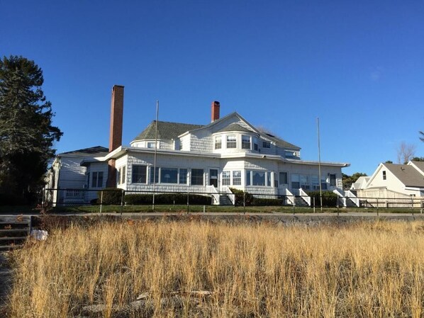 A large, two-story house with a prominent chimney, a wrap-around porch, and a well-maintained lawn. - Holiday House Inn (Scarborough)