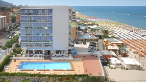 Un hotel con piscina, vista al mar y varios balcones.