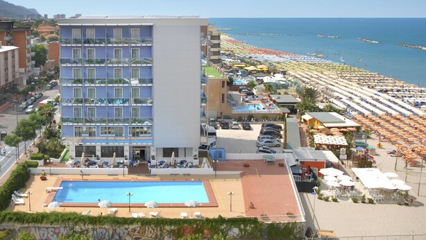 Un hotel con piscina, vista al mar y varios balcones.