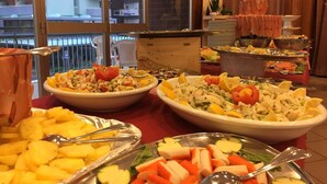 Un bufé con diversos platos, incluyendo ensaladas, frutas y verduras.